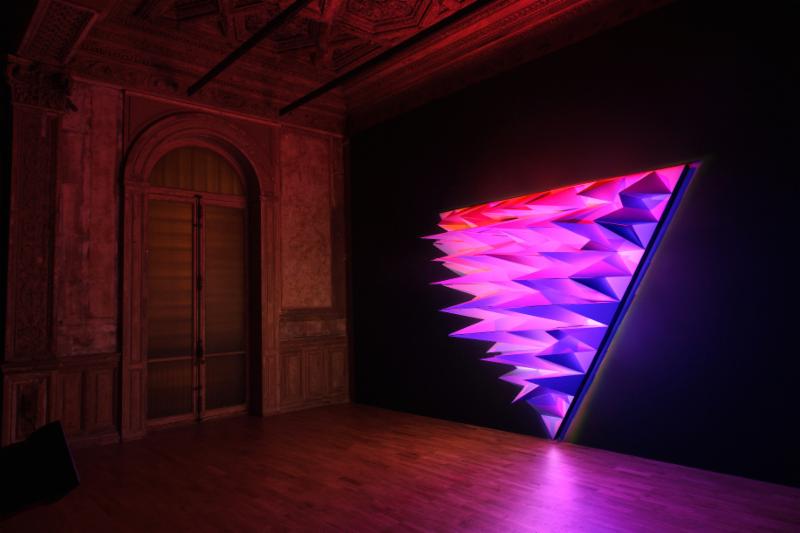 A three-sided triangular wall installation made from cardboard, Talbot's piece explores the three primary colors of light - red, green and blue, with the structure designed to fragment the light and demonstrate how colored light is mixed.